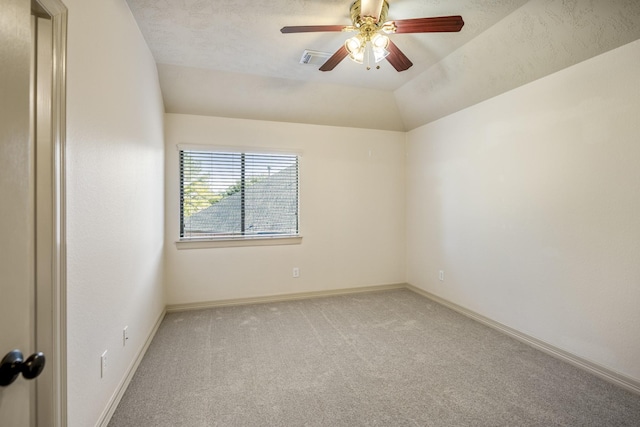 carpeted empty room with vaulted ceiling, a ceiling fan, visible vents, and baseboards