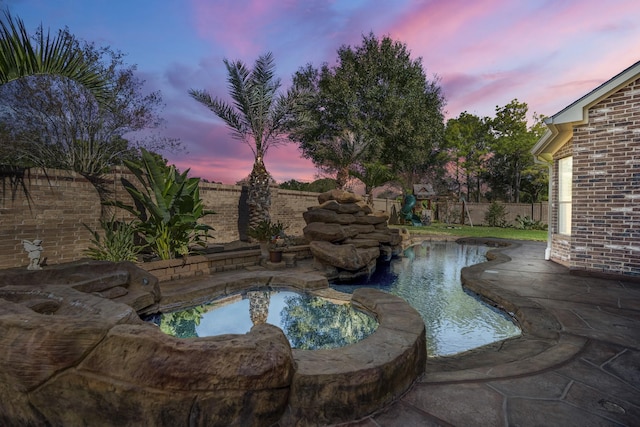 pool at dusk with a jacuzzi and a garden pond