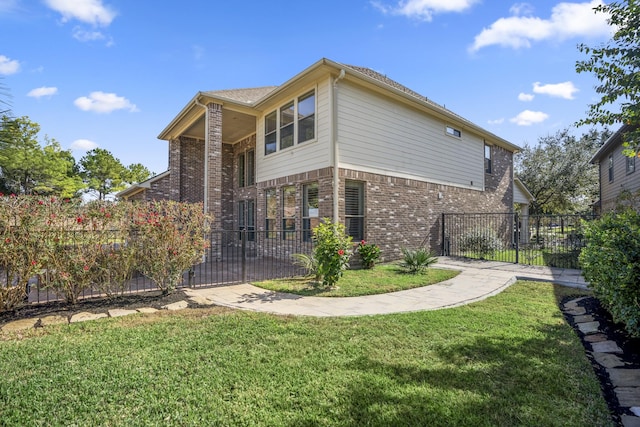 view of side of home featuring a yard, brick siding, and fence