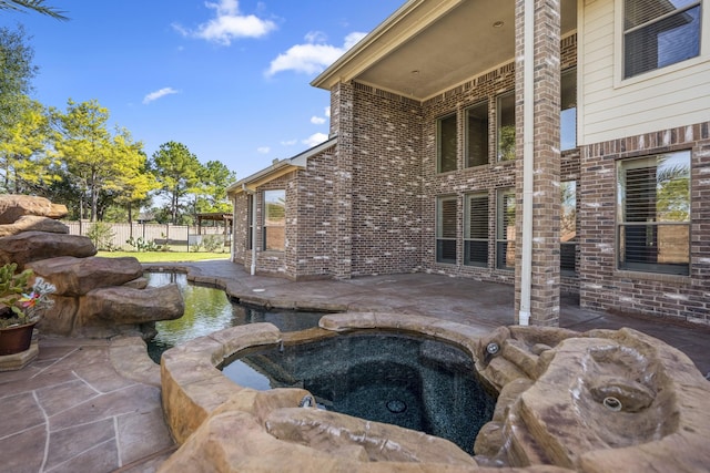 view of swimming pool with a patio, fence, and an in ground hot tub