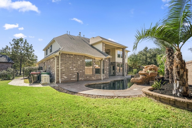 back of property featuring brick siding, a shingled roof, a lawn, a patio area, and fence