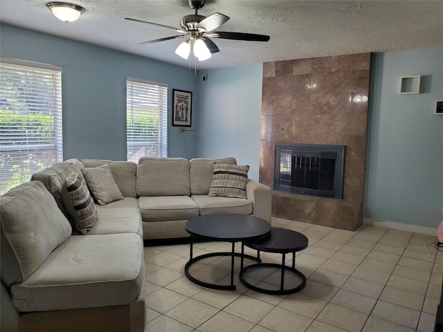 tiled living room with ceiling fan, a large fireplace, and a textured ceiling