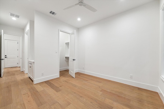 interior space featuring ceiling fan, light hardwood / wood-style floors, a walk in closet, and a closet