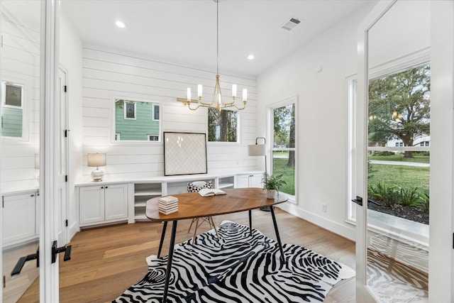 office area with light hardwood / wood-style floors and a notable chandelier