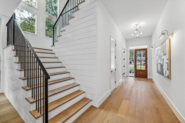 foyer entrance featuring a wealth of natural light, a notable chandelier, and light wood-type flooring