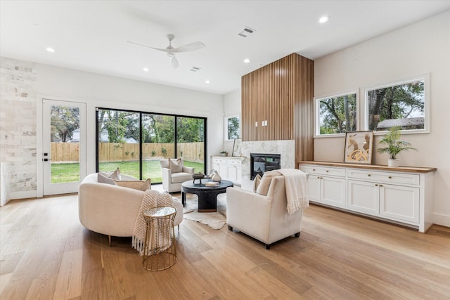 living room with a fireplace, light wood-type flooring, and ceiling fan