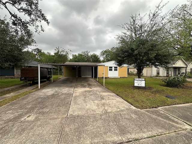 view of front of house with a carport, a front lawn, and a storage shed