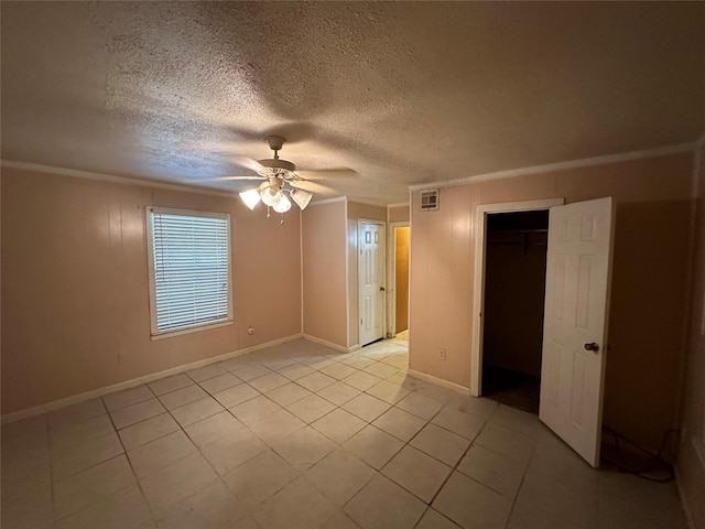 spare room featuring ceiling fan, light tile patterned flooring, crown molding, and a textured ceiling