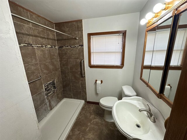 bathroom featuring toilet, sink, and tiled shower