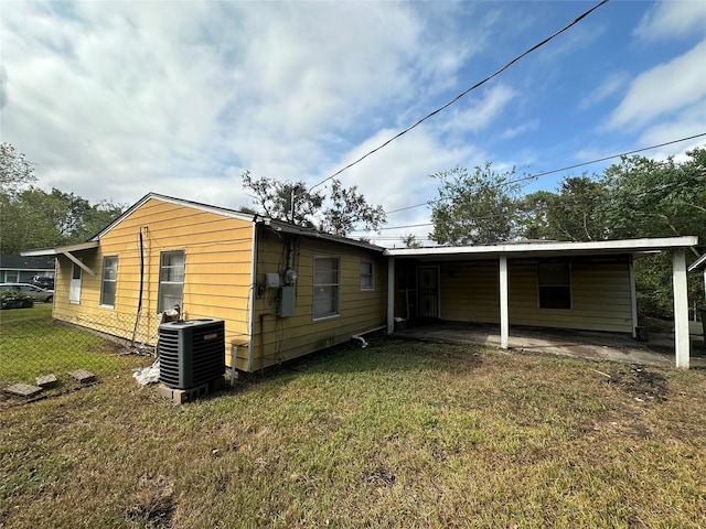 back of house featuring a carport, cooling unit, and a lawn