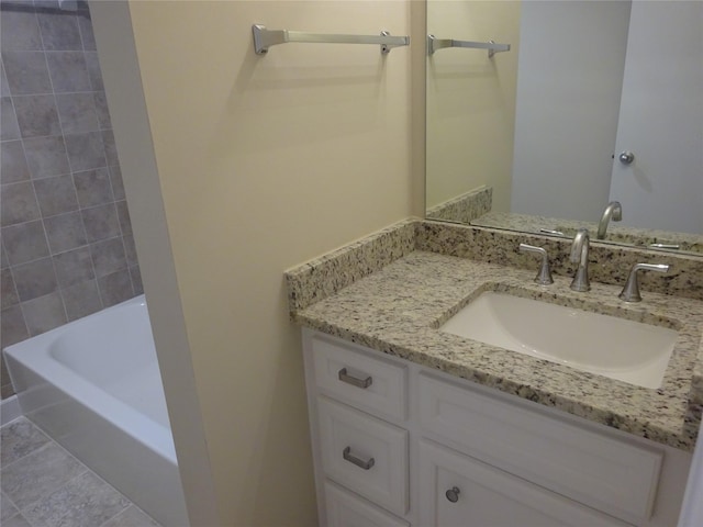 bathroom with tile patterned floors, a washtub, and vanity