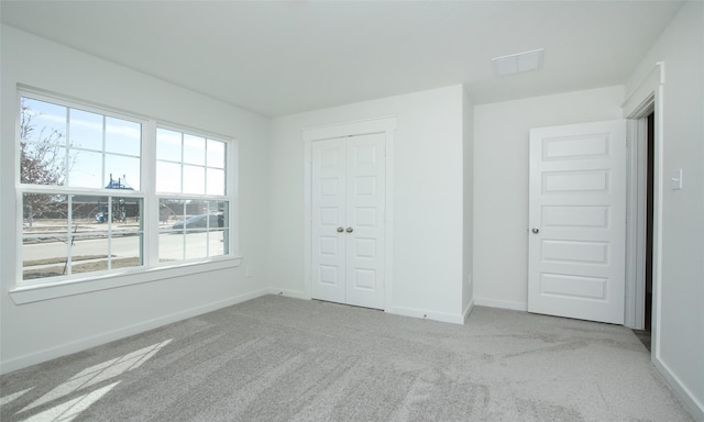 unfurnished bedroom with light colored carpet and a closet