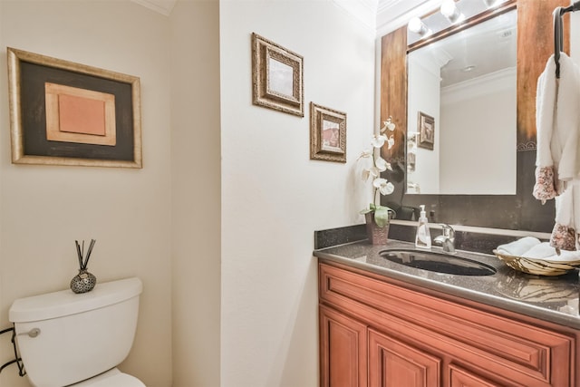 bathroom featuring toilet, vanity, and ornamental molding