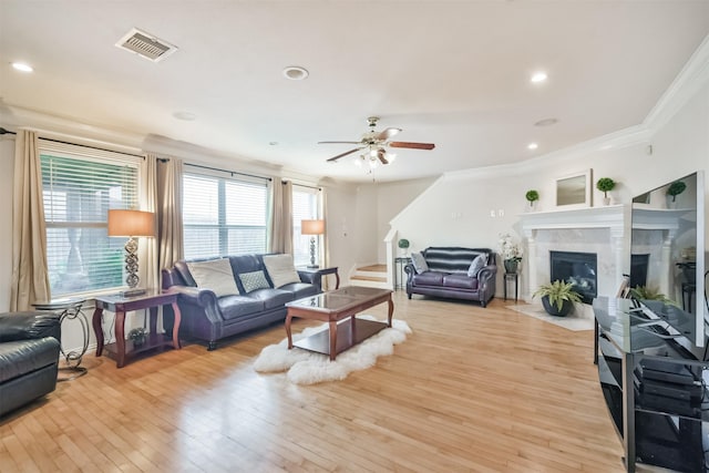 living room featuring a fireplace, light hardwood / wood-style floors, ceiling fan, and crown molding