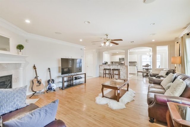 living room with crown molding, light hardwood / wood-style flooring, and ceiling fan with notable chandelier