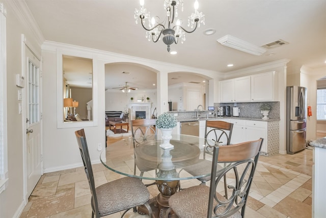 dining area featuring ceiling fan with notable chandelier, ornamental molding, and sink