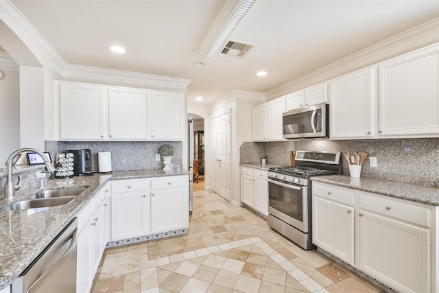 kitchen with white cabinets, decorative backsplash, sink, and stainless steel appliances