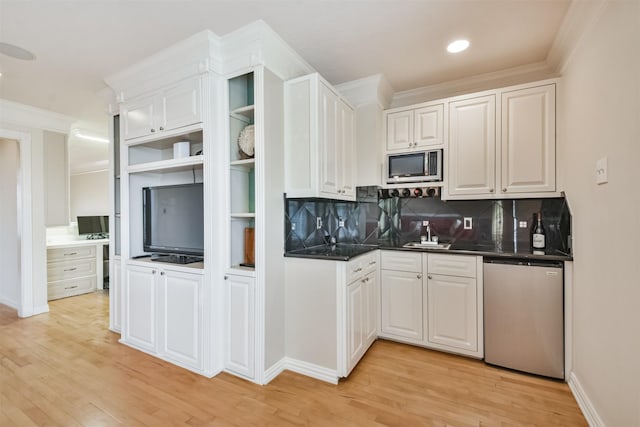 kitchen featuring white cabinets, backsplash, appliances with stainless steel finishes, and light hardwood / wood-style flooring