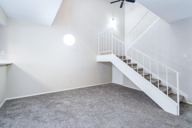 stairs featuring carpet flooring, ceiling fan, and a towering ceiling