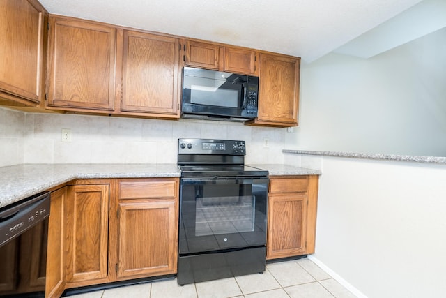 kitchen with black appliances, light stone counters, light tile patterned floors, and tasteful backsplash