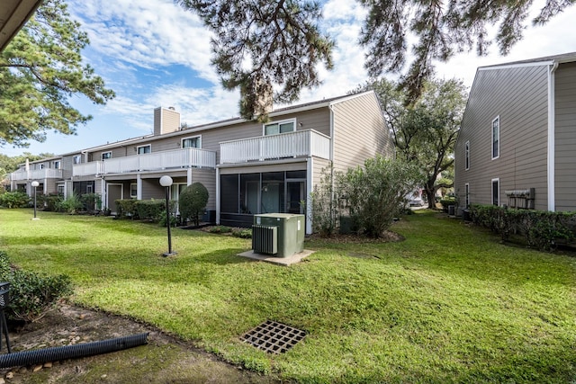 rear view of property with a lawn, a sunroom, and a balcony