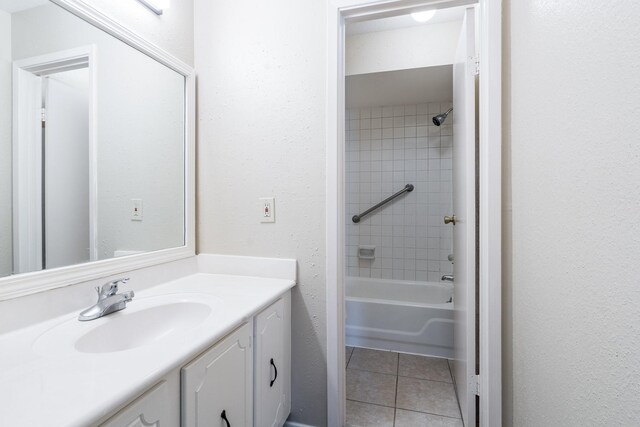 bathroom featuring tile patterned flooring, vanity, and tiled shower / bath