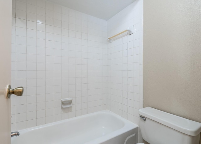 bathroom featuring tiled shower / bath combo and toilet