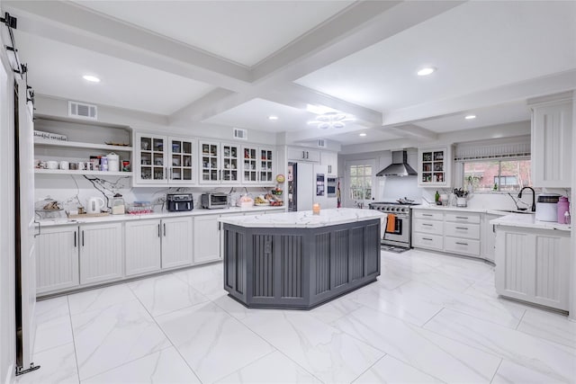 kitchen with wall chimney exhaust hood, high end stove, a kitchen island, beamed ceiling, and white cabinetry