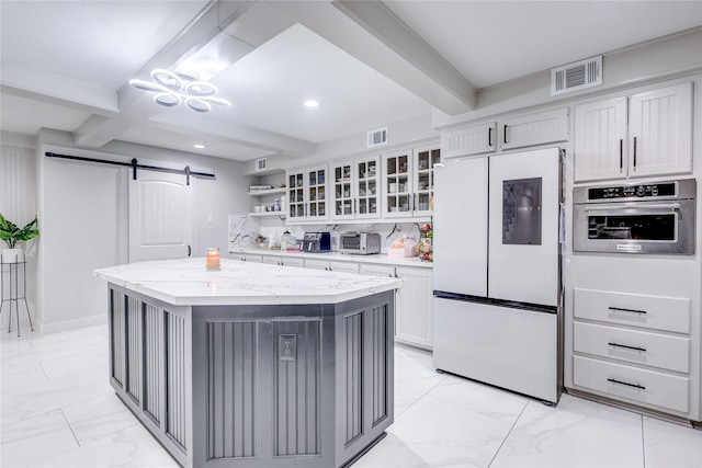 kitchen featuring beam ceiling, a barn door, stainless steel oven, and white refrigerator