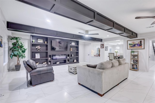 living room with built in shelves and ceiling fan