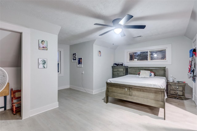 bedroom featuring a textured ceiling, light wood-type flooring, ceiling fan, and lofted ceiling