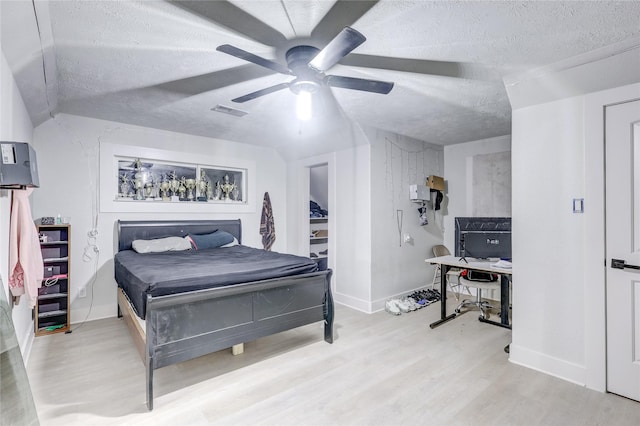 bedroom featuring ceiling fan, a textured ceiling, and light wood-type flooring