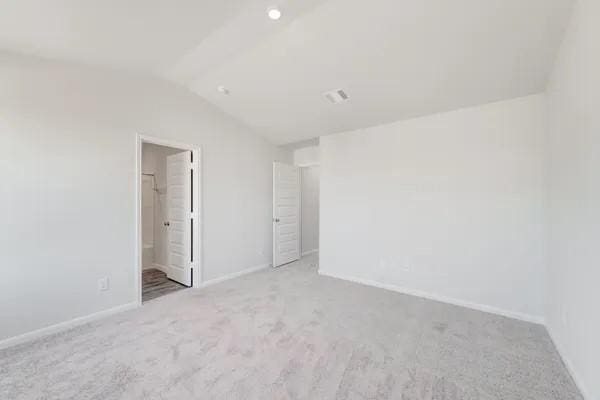 unfurnished room featuring light carpet and vaulted ceiling