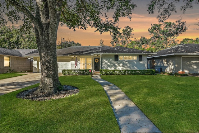 view of front of property with a garage and a lawn