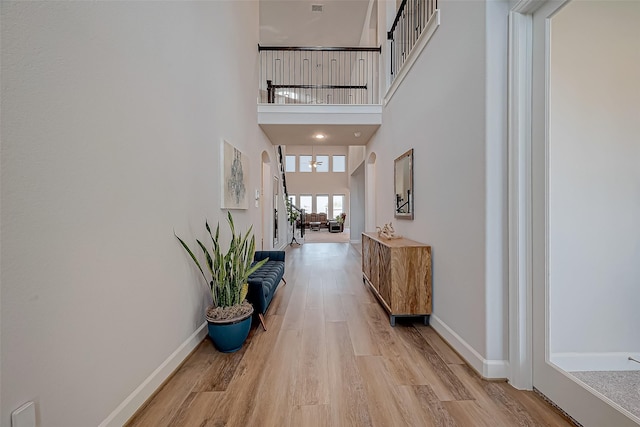 hallway featuring light wood-type flooring and a high ceiling