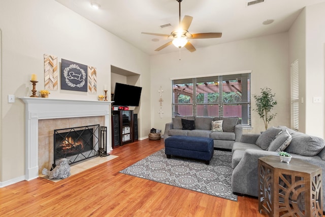 living room featuring a tile fireplace, hardwood / wood-style flooring, and ceiling fan