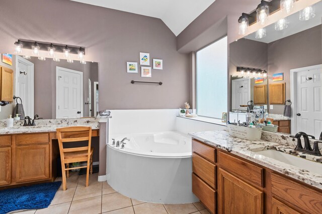 bathroom with tile patterned floors, a tub to relax in, vanity, and vaulted ceiling