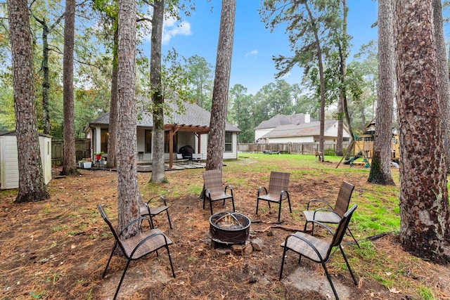 view of yard featuring a storage unit, a playground, an outdoor fire pit, and a patio