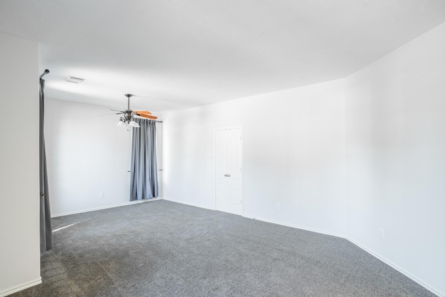 spare room with dark colored carpet and ceiling fan