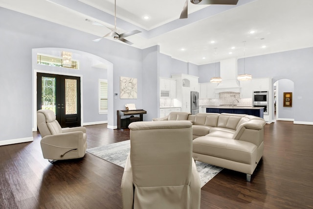 living room featuring a towering ceiling, french doors, ceiling fan, and dark wood-type flooring