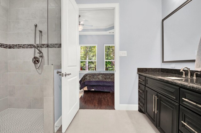 bathroom with tile patterned flooring, ceiling fan, tiled shower, and vanity