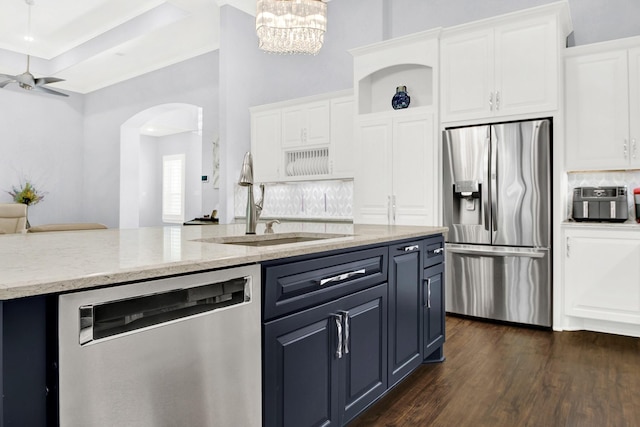 kitchen featuring white cabinetry, backsplash, light stone countertops, pendant lighting, and appliances with stainless steel finishes