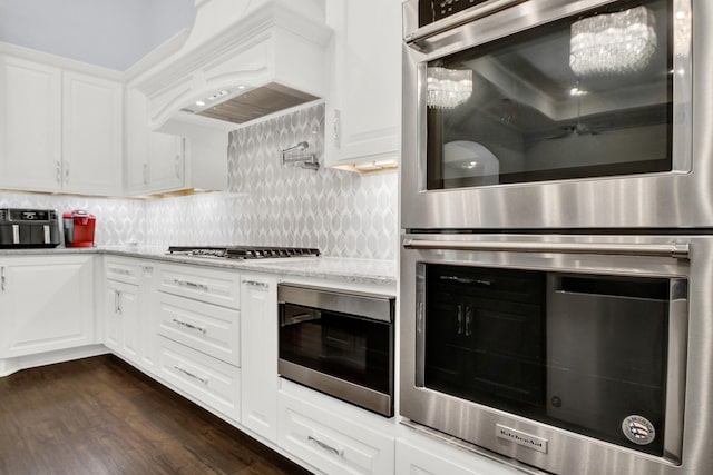 kitchen with white cabinets, custom range hood, and appliances with stainless steel finishes