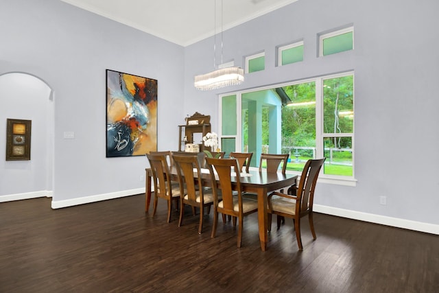 dining space featuring dark hardwood / wood-style flooring, an inviting chandelier, ornamental molding, and a healthy amount of sunlight