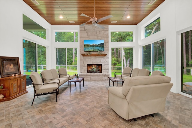 living room featuring a high ceiling, wooden ceiling, a fireplace, and ceiling fan