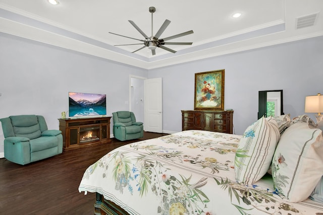 bedroom featuring ceiling fan, a tray ceiling, crown molding, and dark hardwood / wood-style floors