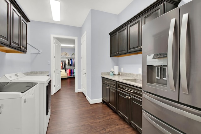 kitchen featuring dark wood-type flooring, dark brown cabinets, washing machine and clothes dryer, and stainless steel refrigerator with ice dispenser