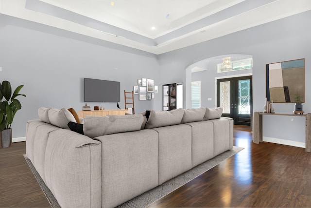 living room featuring dark hardwood / wood-style flooring, french doors, and a tray ceiling