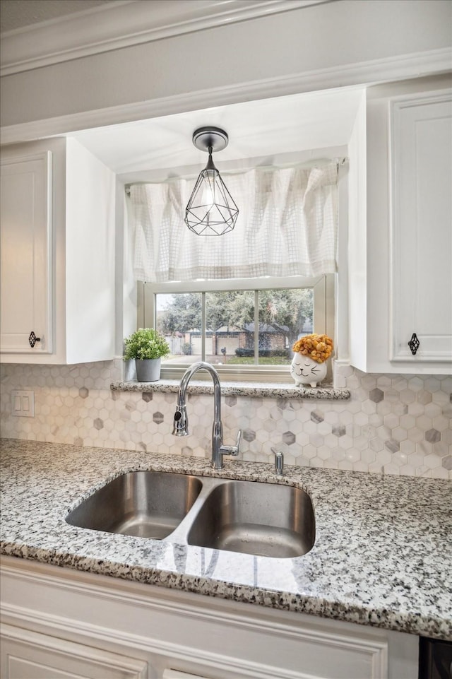 kitchen with backsplash, sink, white cabinets, and decorative light fixtures