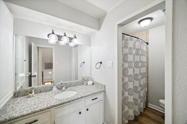 bathroom featuring curtained shower, vanity, wood-type flooring, and toilet